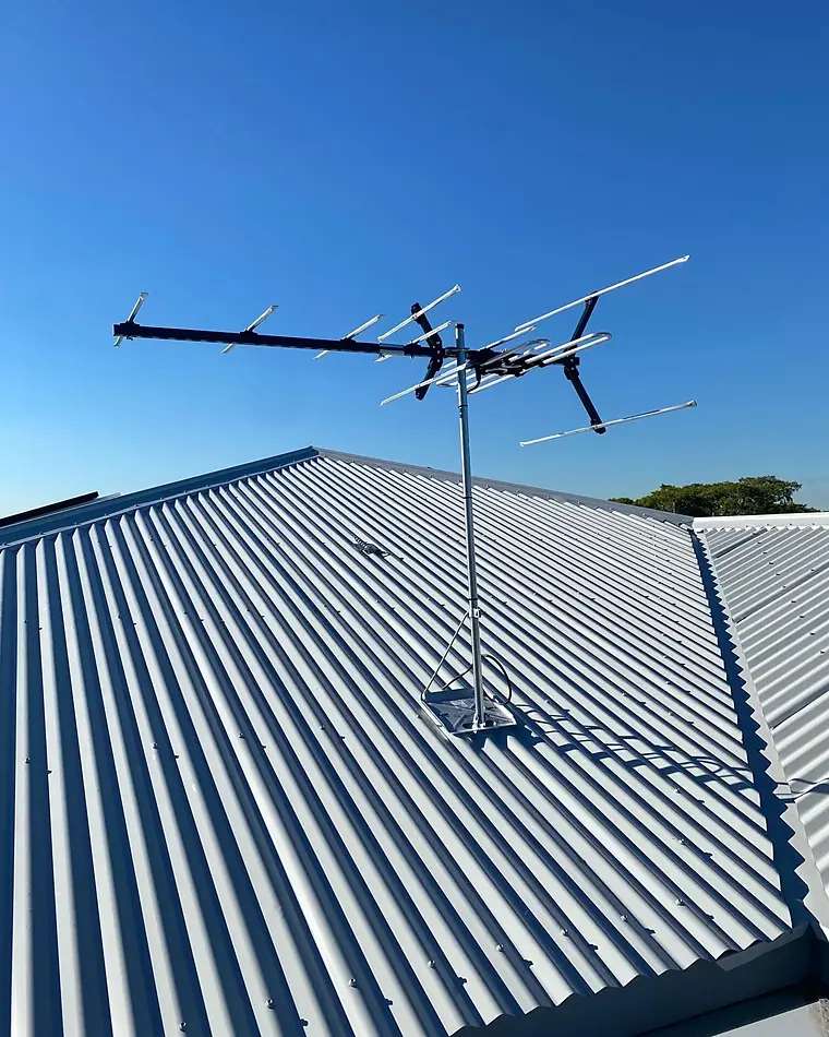 A new TV antenna on a corrugated iron roof against a blue sky