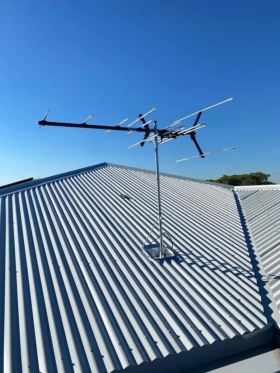 A new TV antenna on a corrugated iron roof against a blue sky