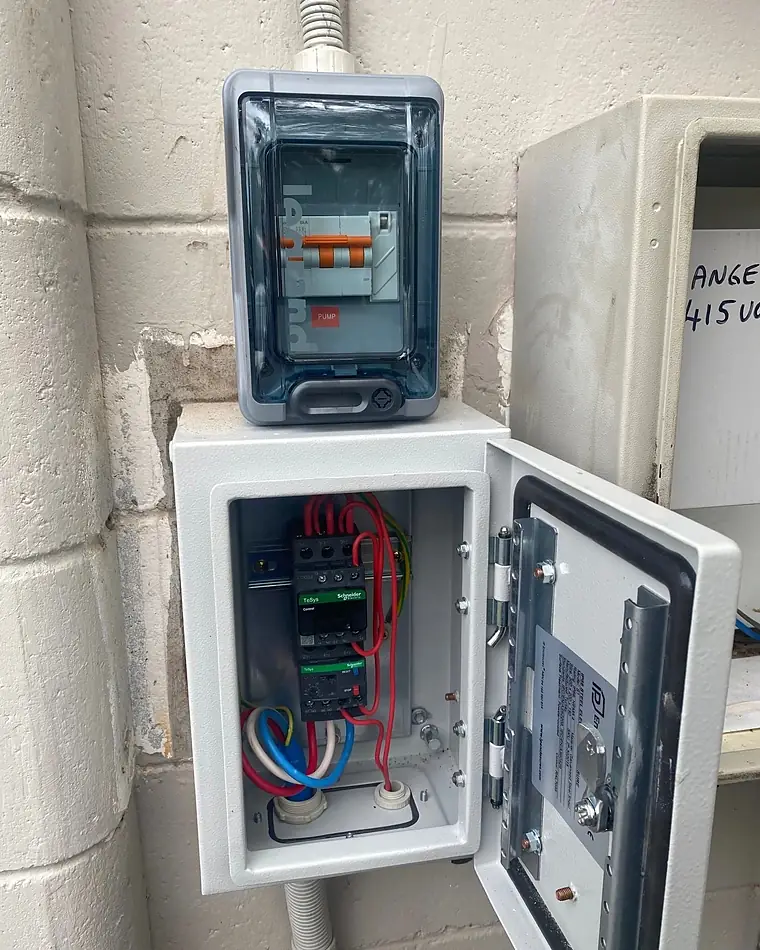 A small outdoor enclosure with its door open, showing new breakers and wiring