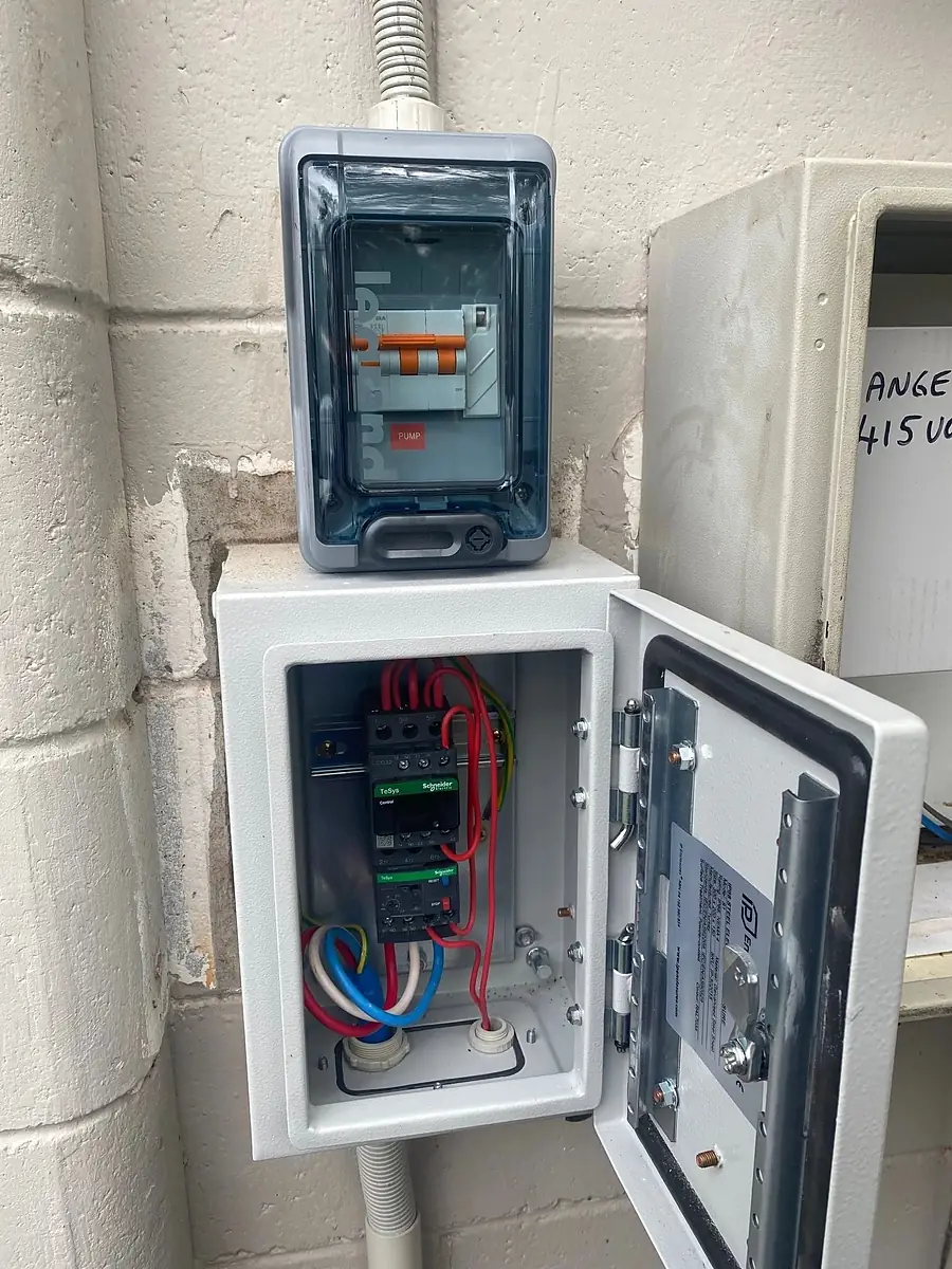 A small outdoor enclosure with its door open, showing new breakers and wiring