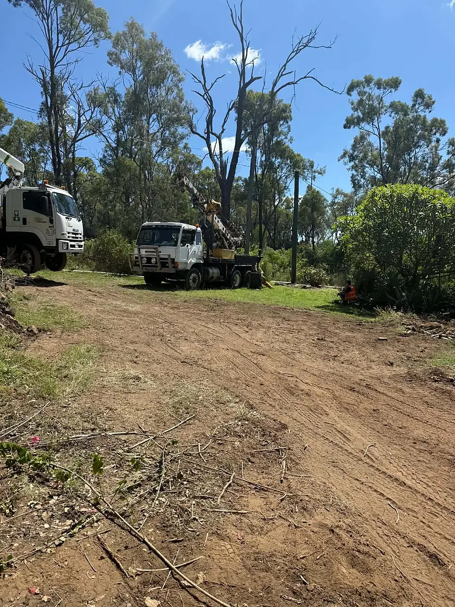 A pole truck and drilling rig on a cleared rural block