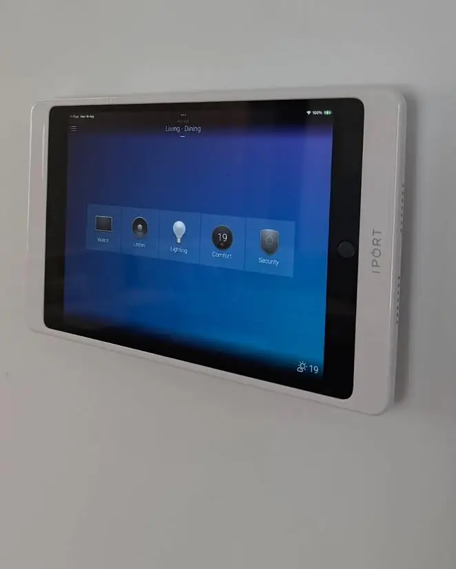 A wall-mounted iPad dock showing the Control4 home screen