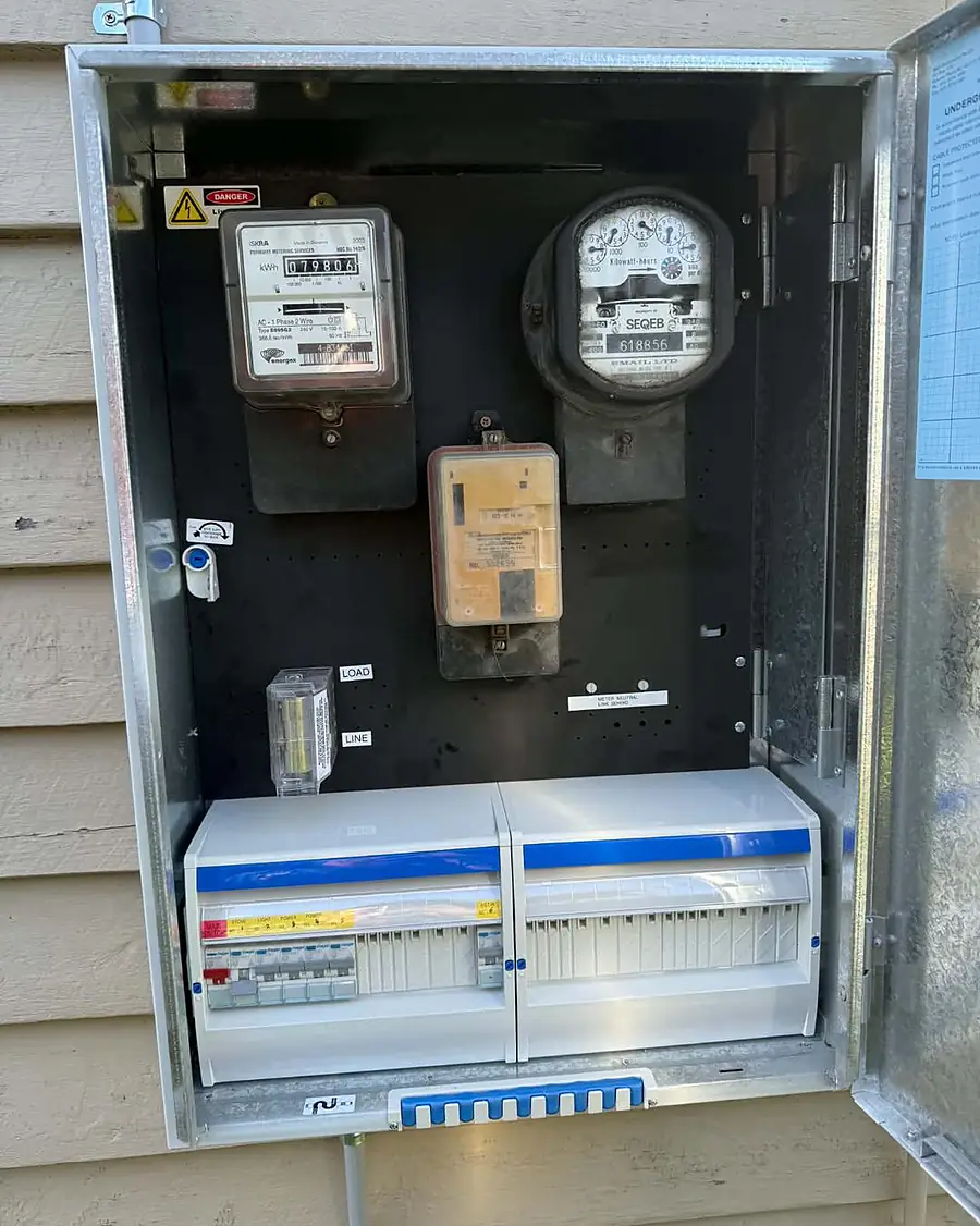 An open meter box with the meters above and a new twin switchboard below