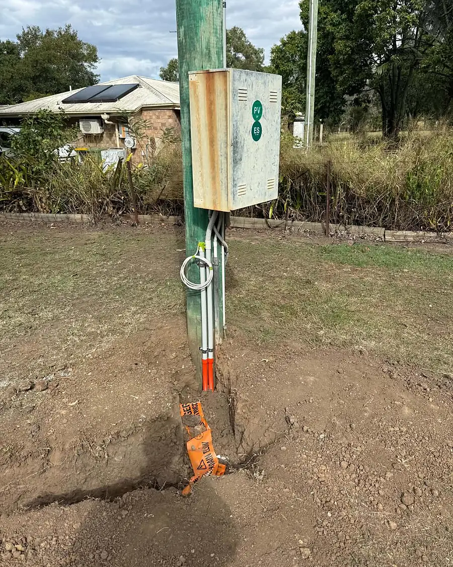 A new underground power supply rising up a pole with warning tape at the base
