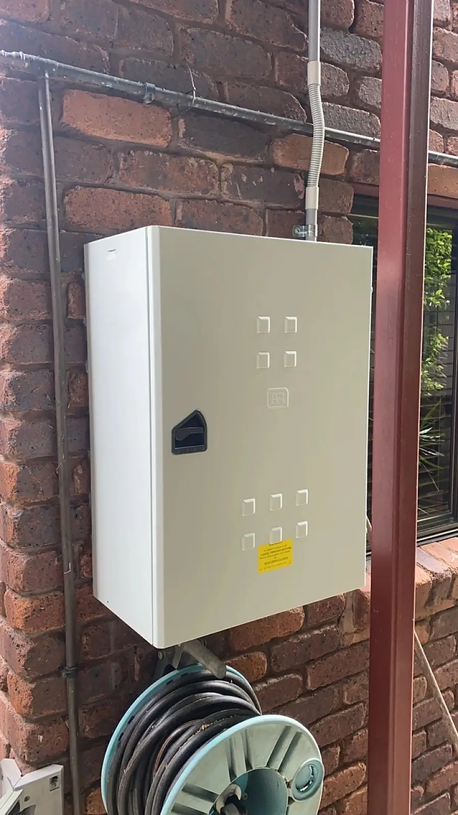A white equipment enclosure mounted on a brick wall